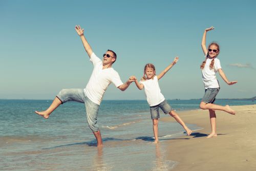 Dansende familie på en strand. Alle er klædt i hvidt