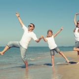 Dansende familie på en strand. Alle er klædt i hvidt